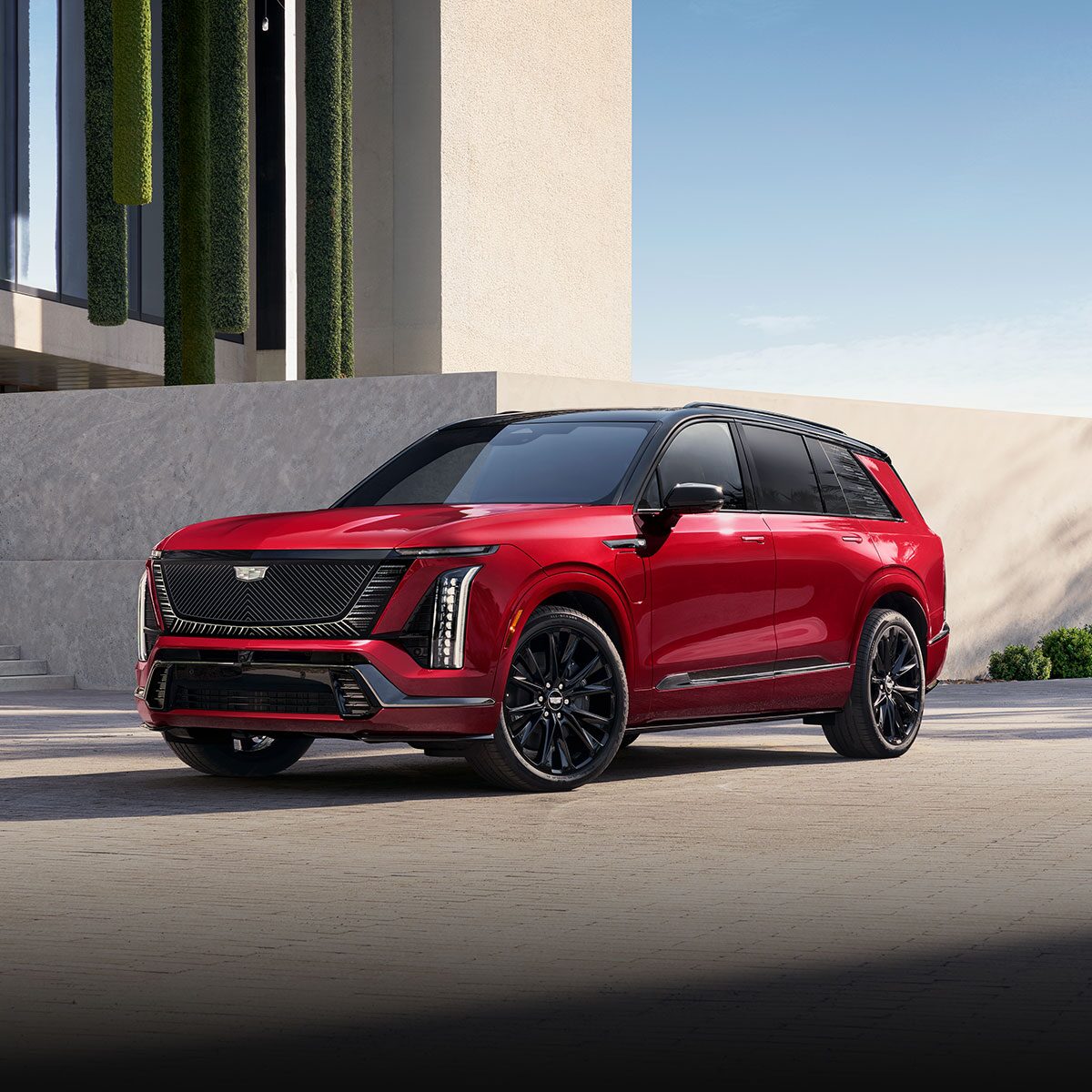 Three-quarter View of a Red Cadillac VISTIQ Parked Outside a Modern Building