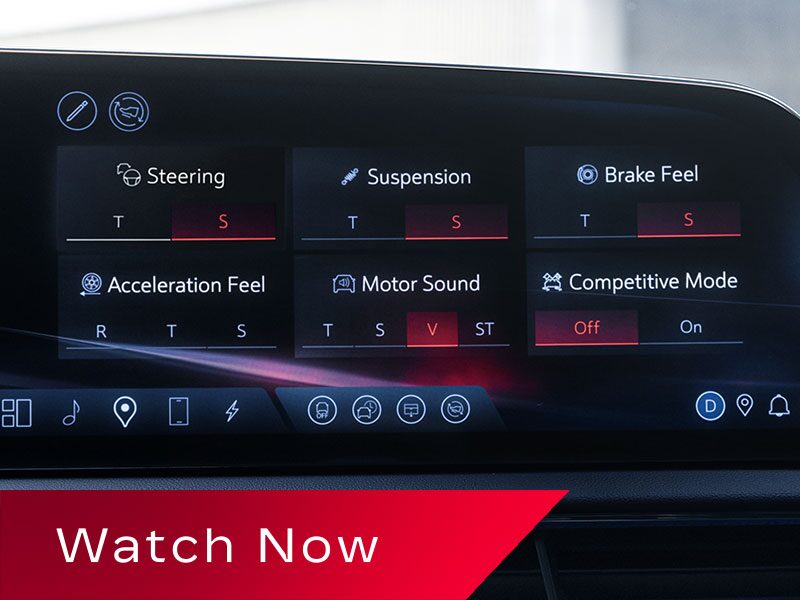 A Cadillac OPTIQ Infotainment Screen Showing Customizable Performance Settings Including Steering, Suspension, Brake Feel, Acceleration Feel, Motor Sound, And Competitive Mode Above a Red Banner Reading “Watch Now.”