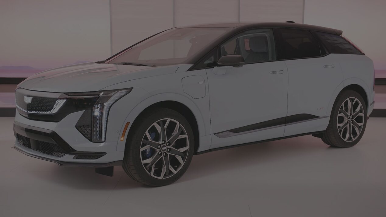 A White Cadillac OPTIQ Positioned in a Bright Studio Setting With Distinctive Vertical LED Headlamps and Multi-Spoke Wheels.