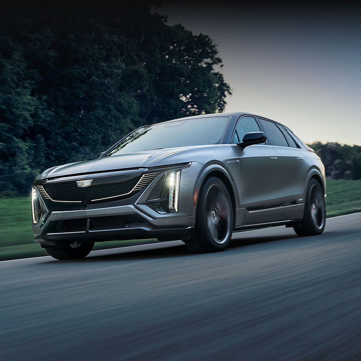 A Silver Cadillac LYRIQ V-Series Luxury Sport SUV Driving During Dusk
