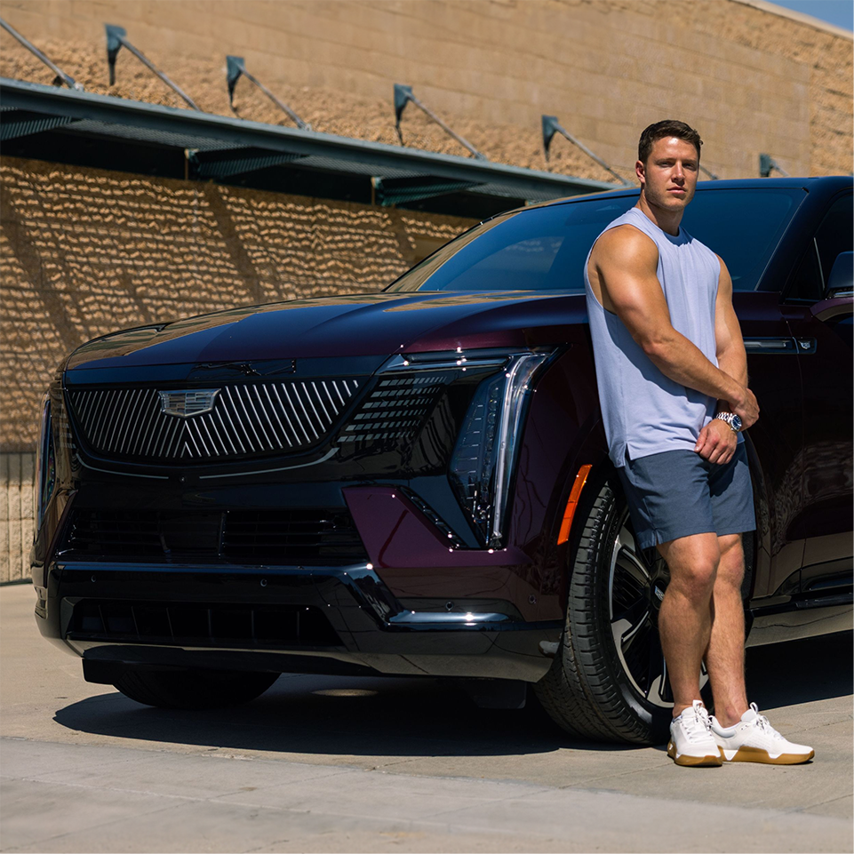 Christian McCaffrey in a Tank Top Leaning on the Front of a Cadillac Escalade