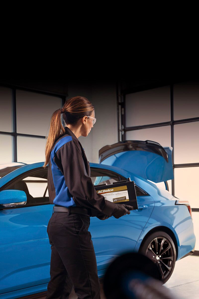 Cadillac Certified Service Technician Carrying an ACDelco Gold Battery to Install in a Vehicle
