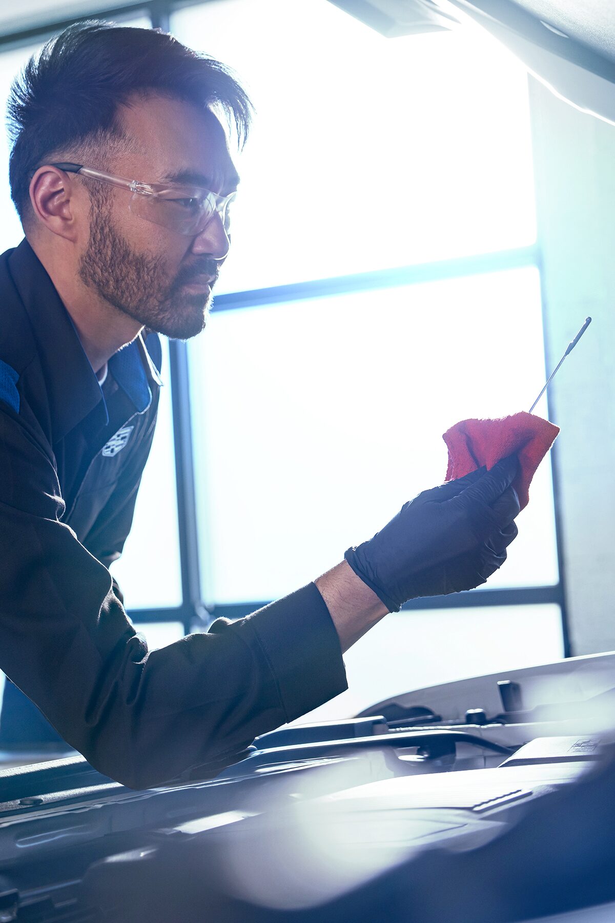 Cadillac Certified Service Technician Checking the Vehicle's Oil Level on a Dipstick