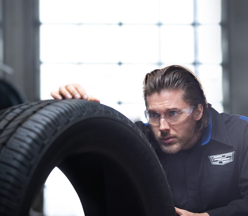 A Male Service Tech with Safety Glasses On Looking at the Tread of a Tire