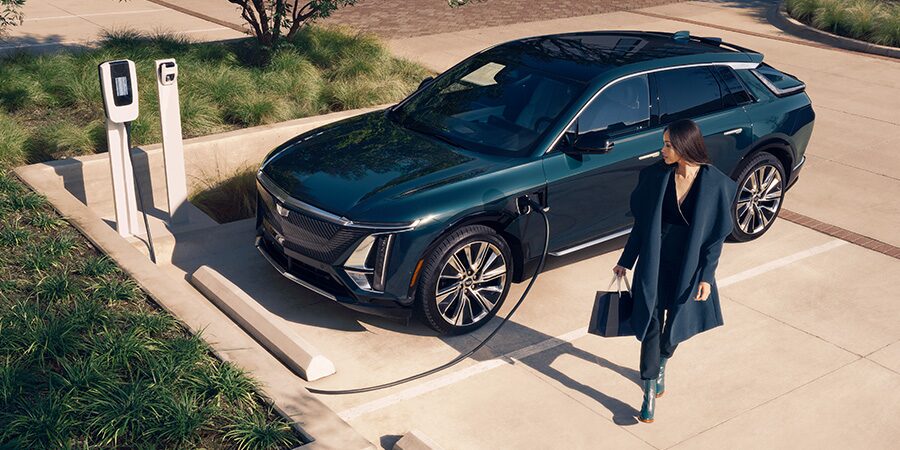 An Overview Shot View of a Woman Looking at a Cadillac EV Being Charged