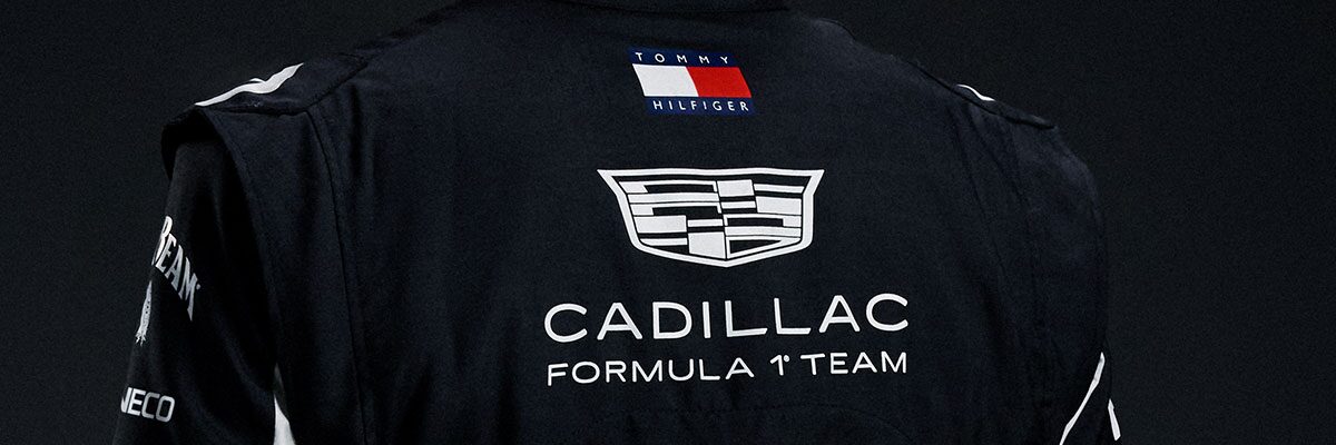 A Close-Up Of the Back Of A Black Cadillac Race Suit Showcases the Cadillac Formula Racing Team Logo And Sponsor Patches Under Studio Lighting.