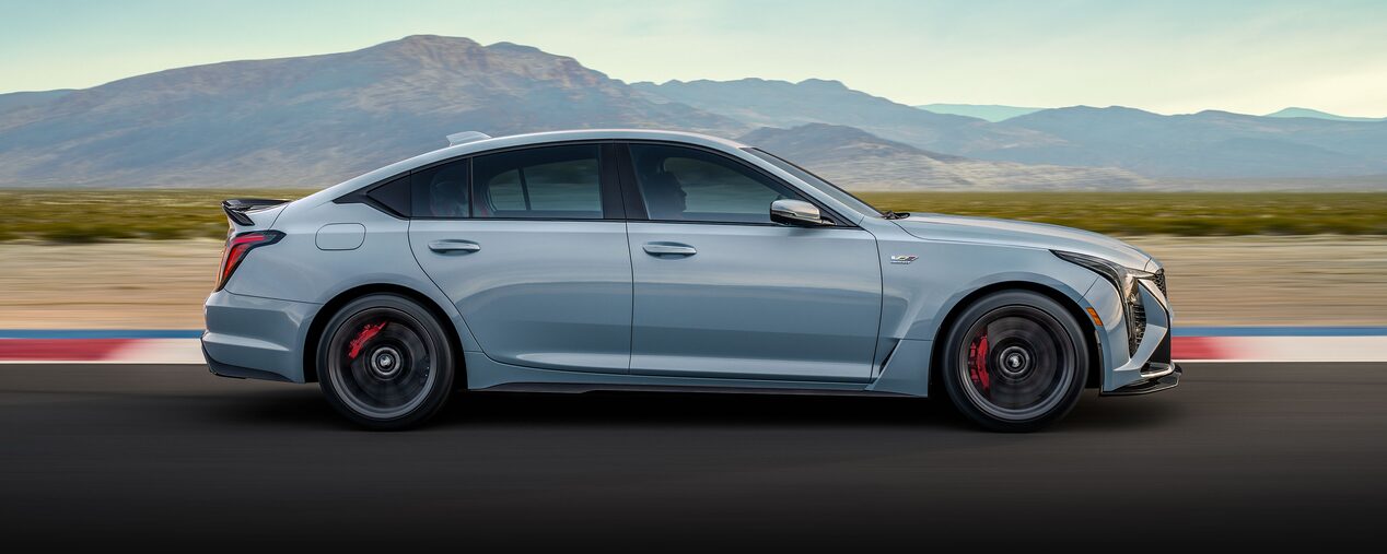Side View of a Light Blue Cadillac CT5-V Driving Down the Road with Mountains Visible in the Distance