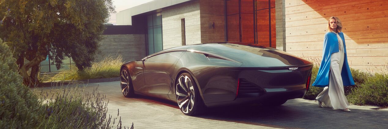 A Fashionably Dressed Woman Walking Around the Rear of a Cadillac InnerSpace Concept Vehicle