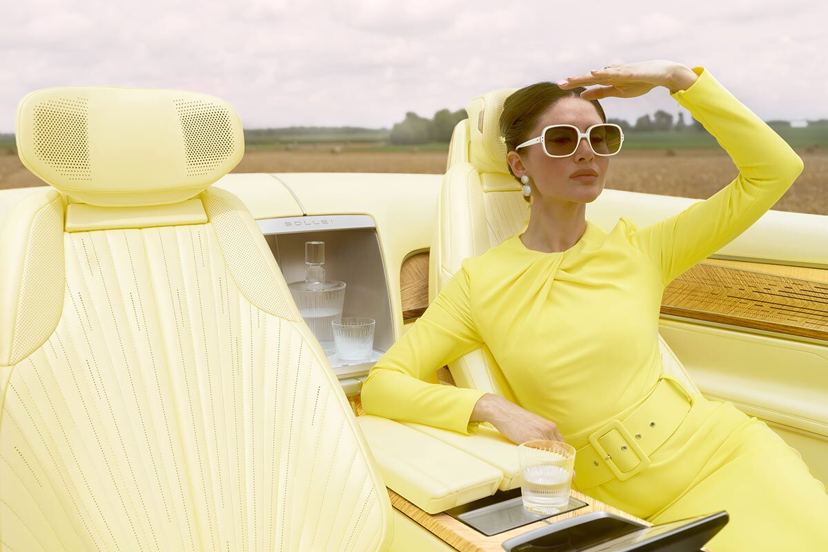 A Woman Wearing Yellow Looking in the Distance and Sitting in the Pale Yellow Interior of the Cadillac Sollei Concept Vehicle