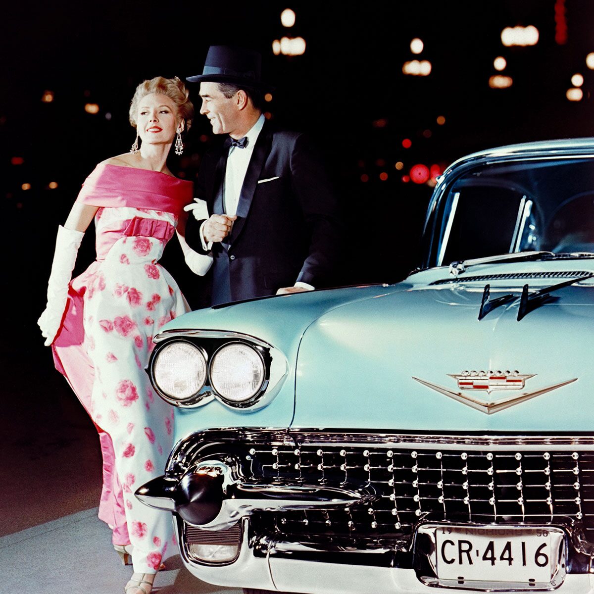 Fancy Dressed Couple Posing In Front Of Classic Cadillac Vehicle
