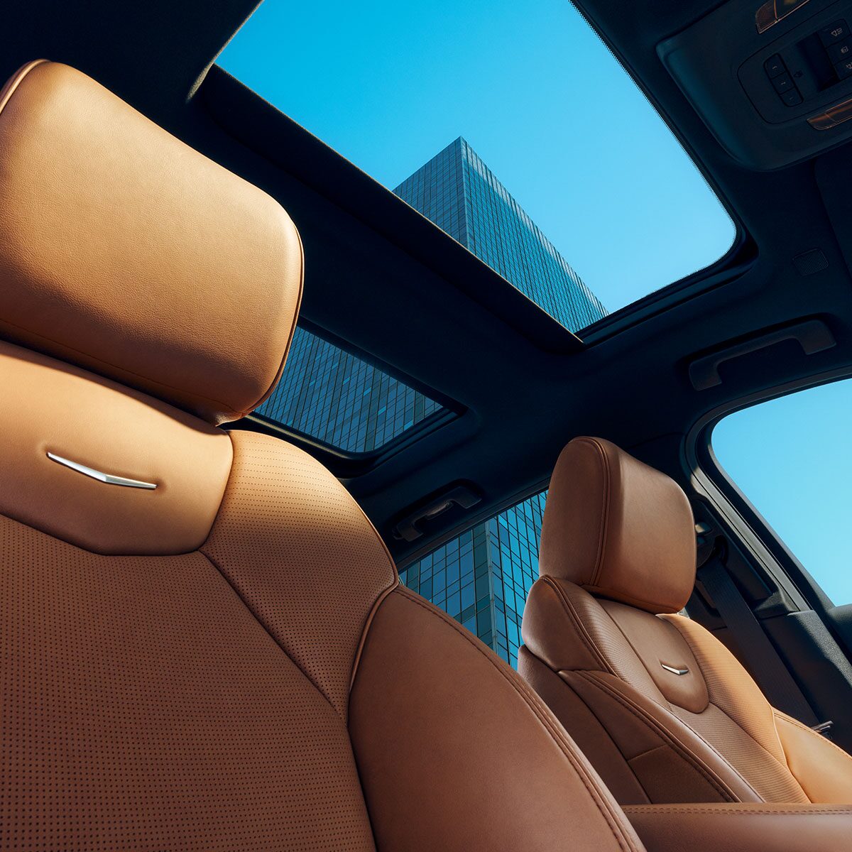 Sun Shining on 2025 Cadillac CT5 Crest on Front Leather Seats and View of Sun Roof