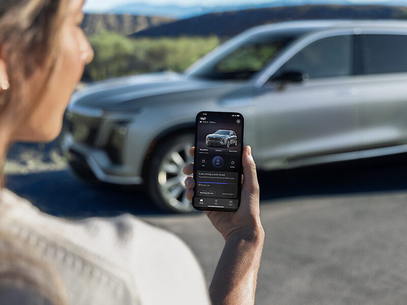 Close-up of a Woman Checking a 2026 VISTIQ Charging Range on the myCadillac Phone App