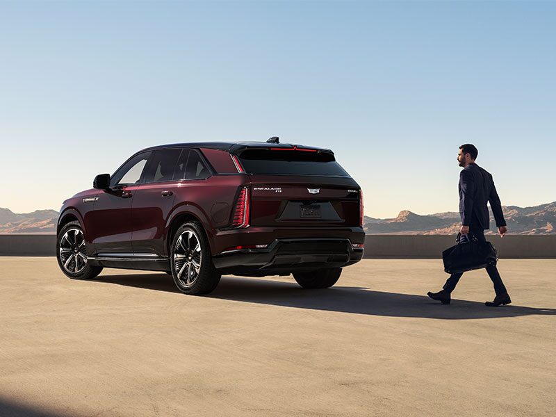 A Business Man Walking Towards the Rear Side of a Parked 2026 ESCALADE IQ