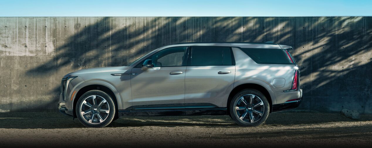 A Side Profile View of the 2026 ESCALADE IQL Parked by a Wood Fence