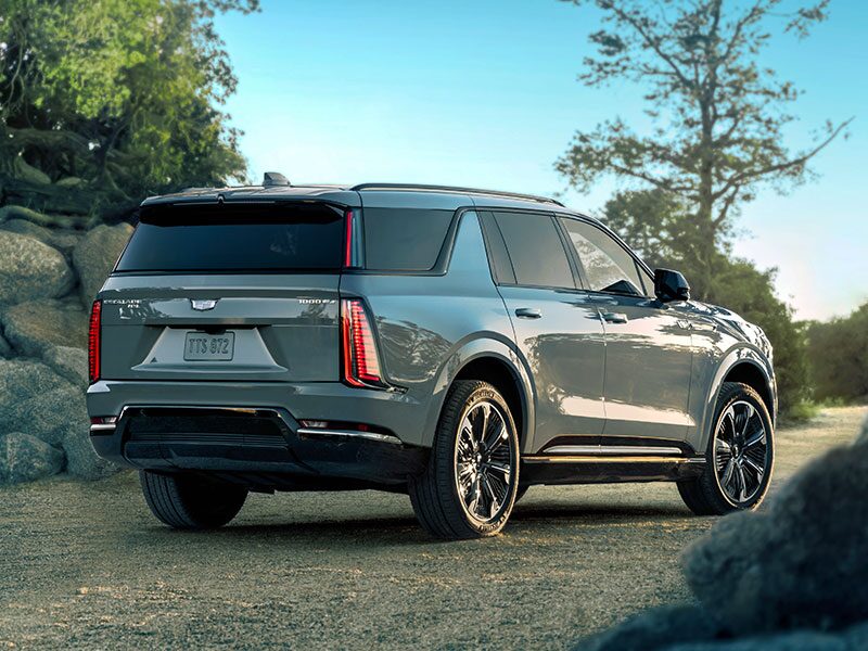 Rear Three-Quarter View of the 2026 ESCALADE IQL Parked Near a Rocky Trail