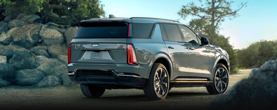 Rear Three-Quarter View of the 2026 ESCALADE IQL Parked Near a Rocky Trail