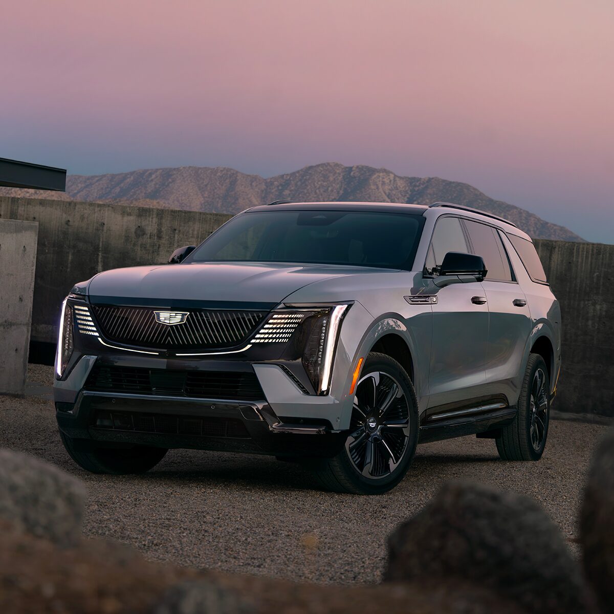 Front Three-Quarter View of the 2026 ESCALADE IQL Parked near a Concrete Wall During Dusk
