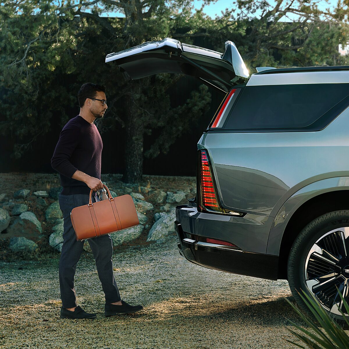 Rear View of a Man Loading a Bag Into the Spacious Trunk of a 2026 ESCALADE IQL