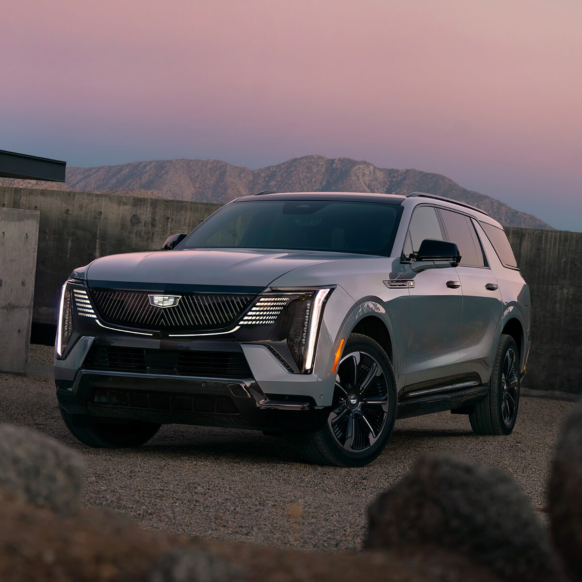 Front Three-Quarter View of the 2026 ESCALADE IQL Parked near a Concrete Wall During Dusk