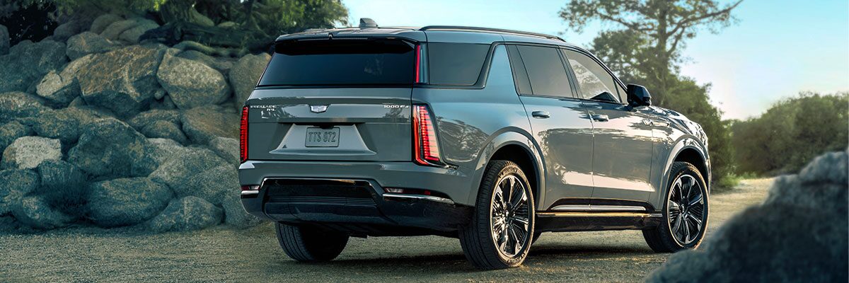 Rear Three-Quarter View of the 2026 ESCALADE IQL Parked Near a Rocky Trail