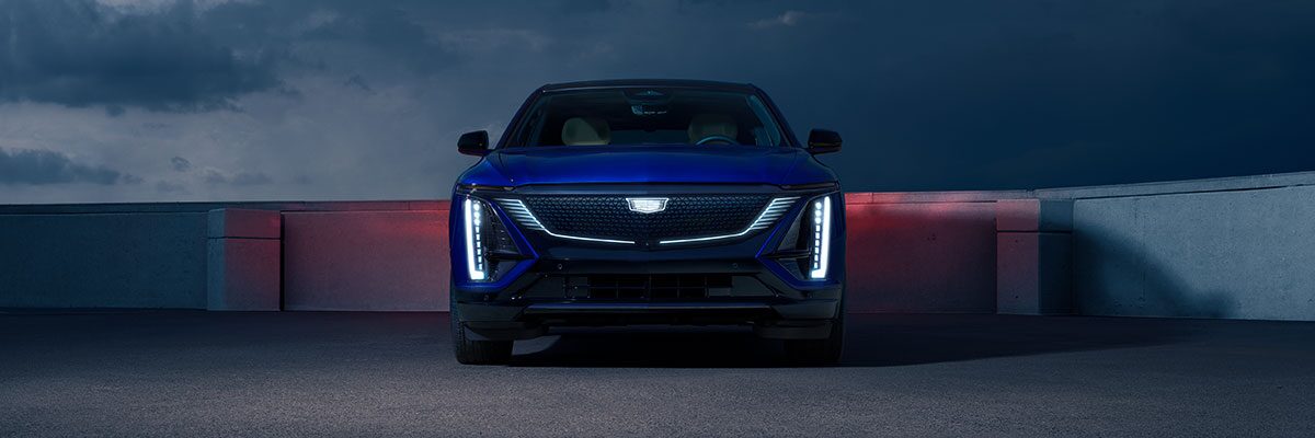 Front View of a Blue Cadillac LYRIQ Parked on the Top Level of a Parking Garage at Night
