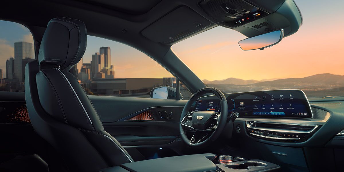 Passenger View of the Driver's Side of the Cadillac LYRIQ Outlooking a City During a Sunset