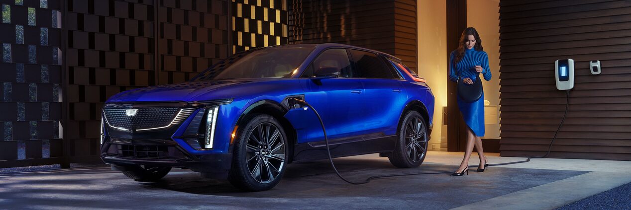 A Woman Looking in Her Purse Next to a Charging Blue Cadillac LYRIQ