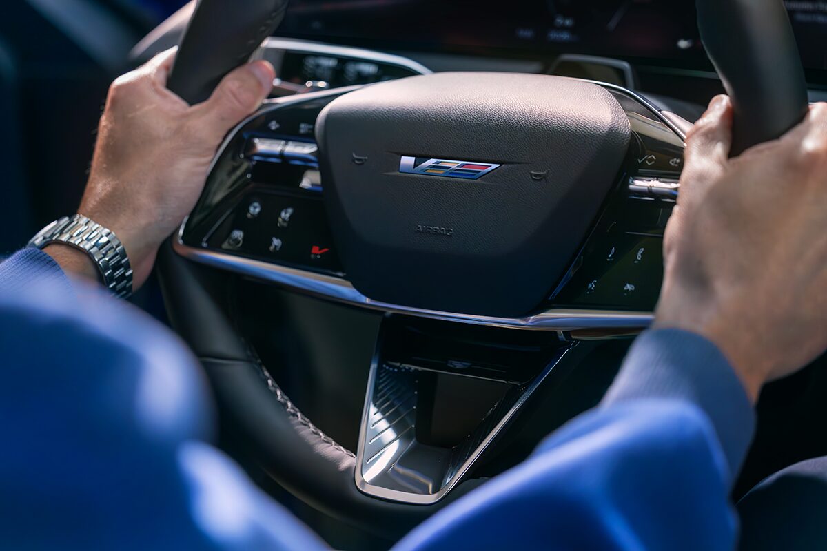 Close-up of a Man Driving and a Close-up of the V-Button on the 2026 OPTIQ-V Steering Wheel