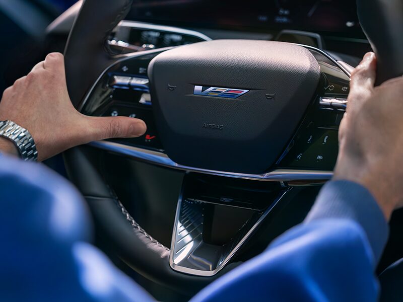 Close-up of a Man About to Press the V-Button on the 2026 OPTIQ-V Steering Wheel