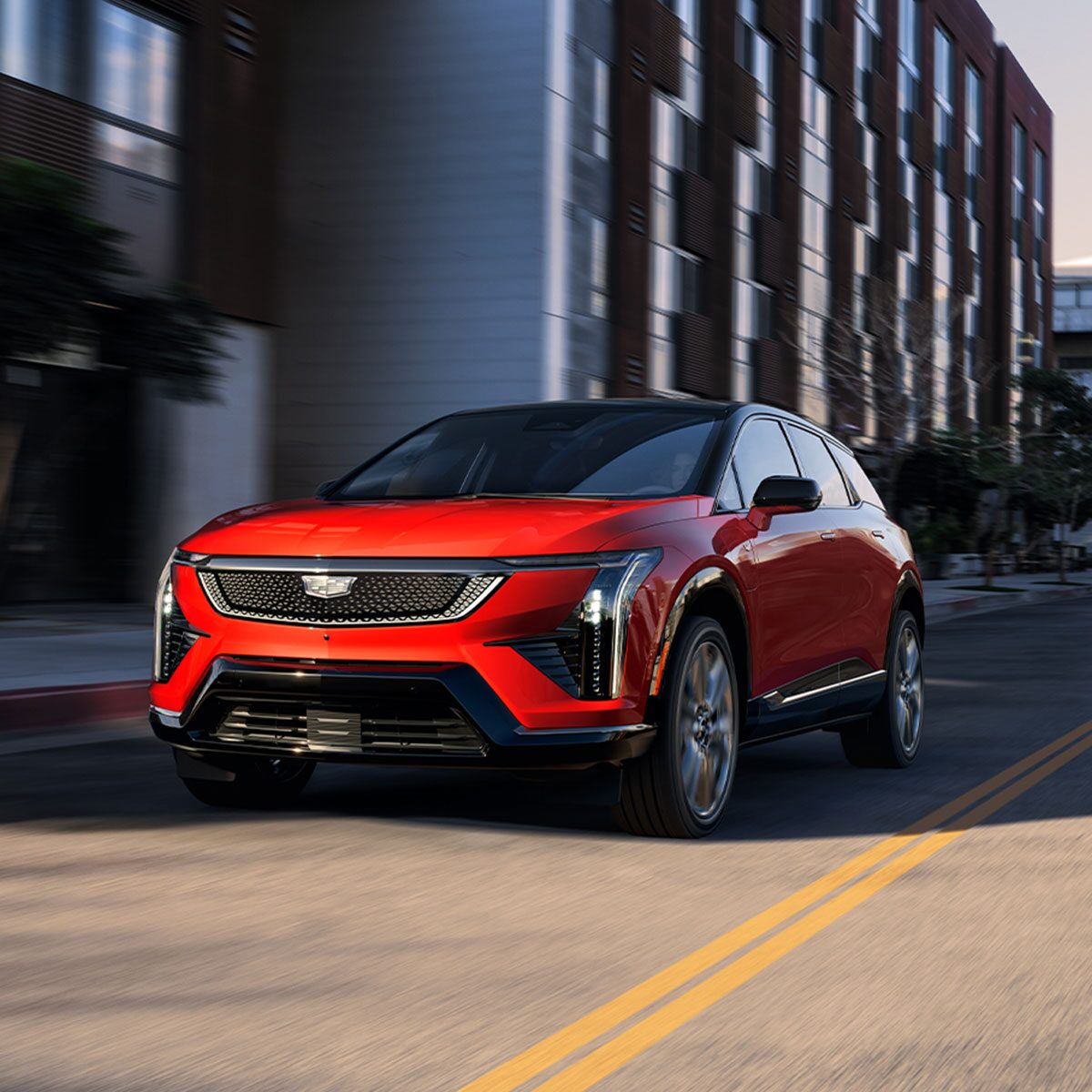 A Red 2026 Cadillac OPTIQ Driving Down a City Street