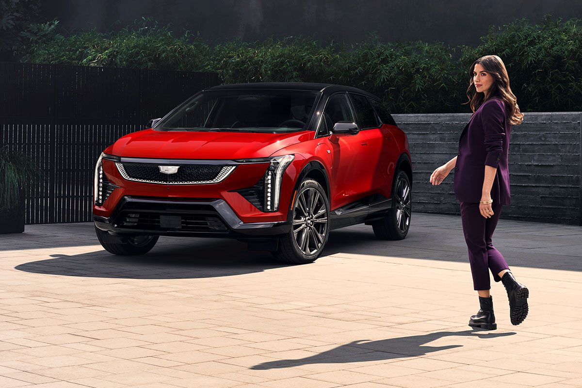 A Woman Walking Towards a Parked, Red 2026 Cadillac OPTIQ