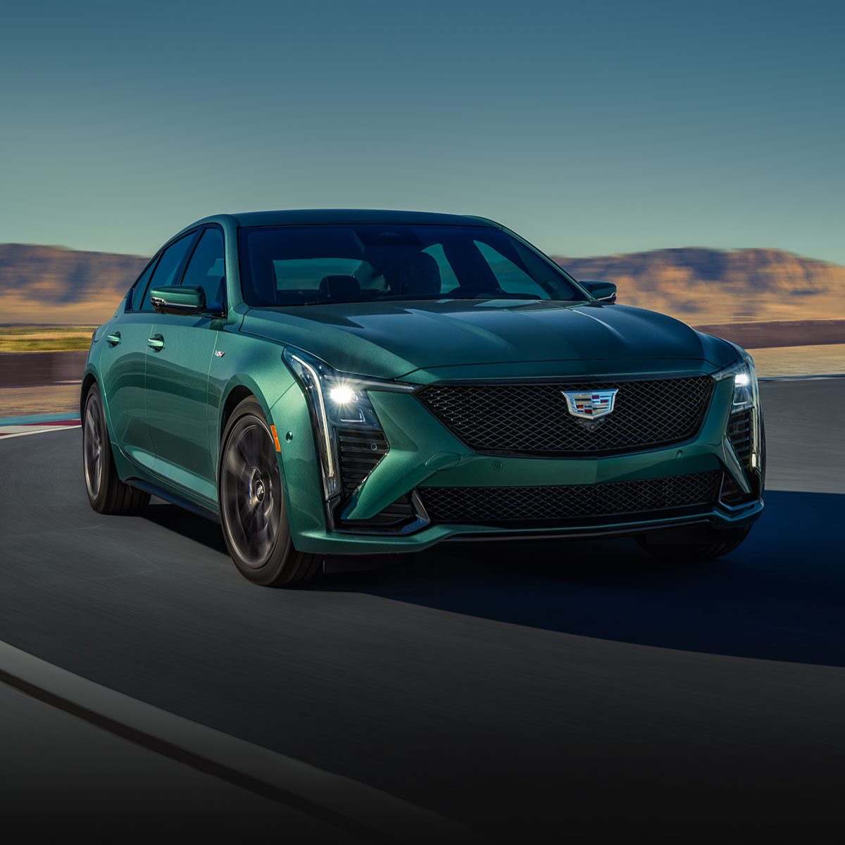 Three-Quarters View of a Green  Cadillac CT5-V Driving Down the Road Surrounded by Desert