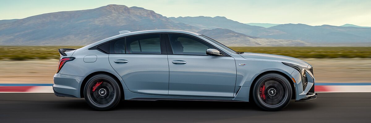Side View of a Light Blue 2025 Cadillac CT5-V Driving Down the Road with Mountains Visible in the Distance