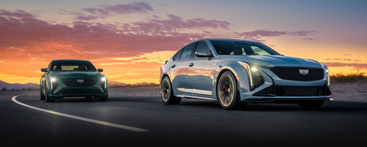 Three-quarters View of Two Cadillac CT5-V Sport Sedans Driving Under a Beautiful Evening Sky