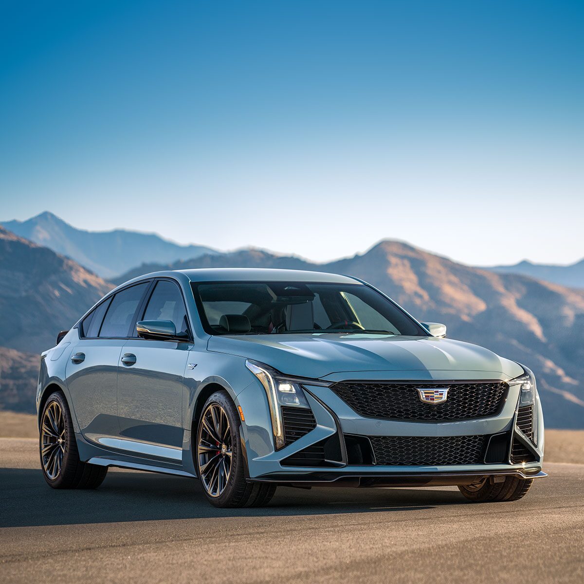 Three-Quarters View of a Light Blue  Cadillac CT5-V in a Desert with Mountains Visible in the Distance