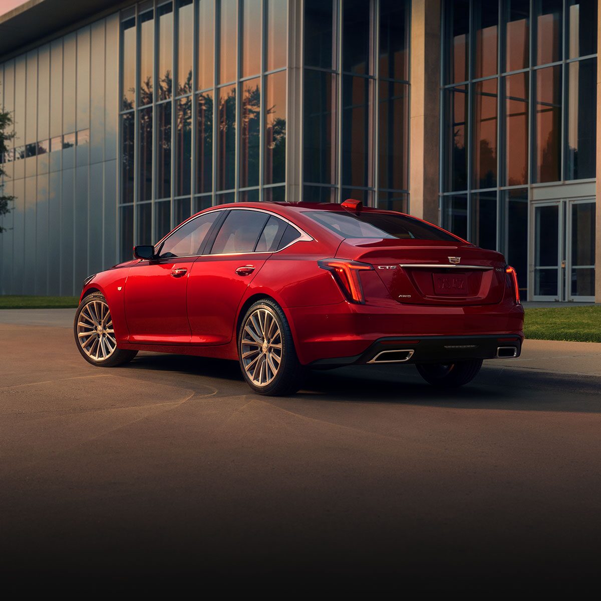 A Driver Side Rear View of a Red 2026 Cadillac Parked Near an Industrial Building