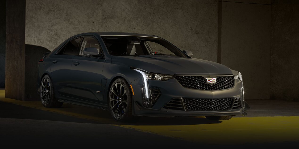 A Dark Gray Cadillac CT4-V Blackwing Sedan Parked on a Yellow-Striped Concrete Floor in a Dimly Lit Garage