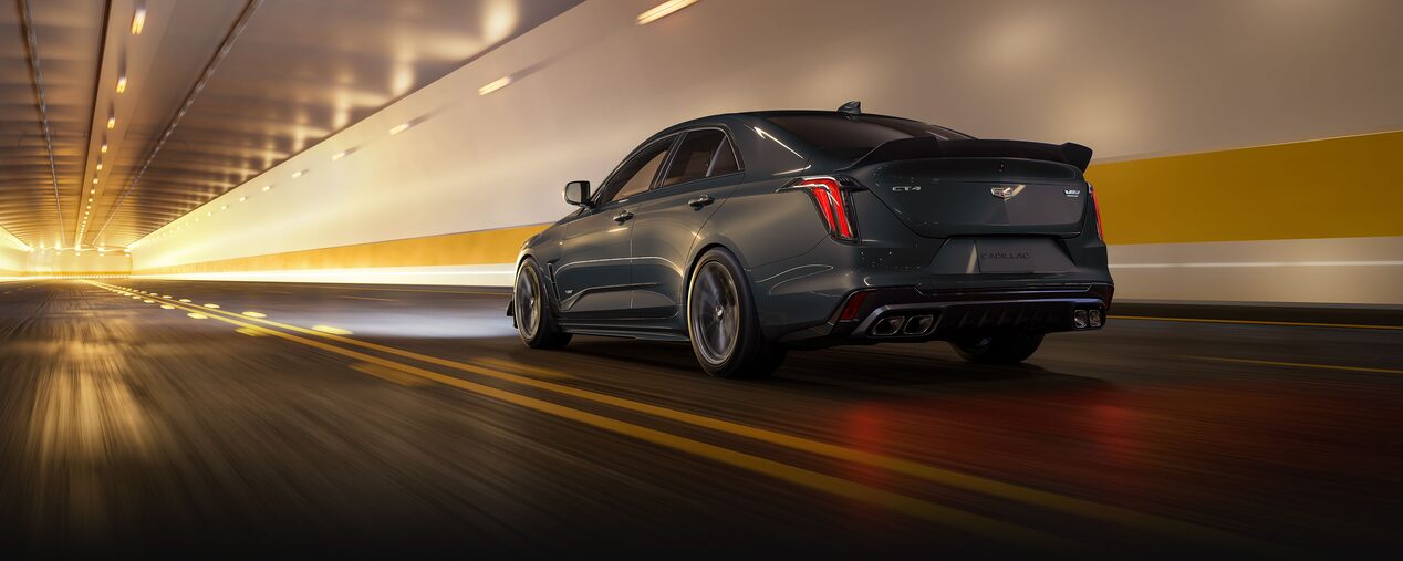 A Yellow Cadillac V-Series Vehicle Driving Through a Tunnel with it's Headlights on.