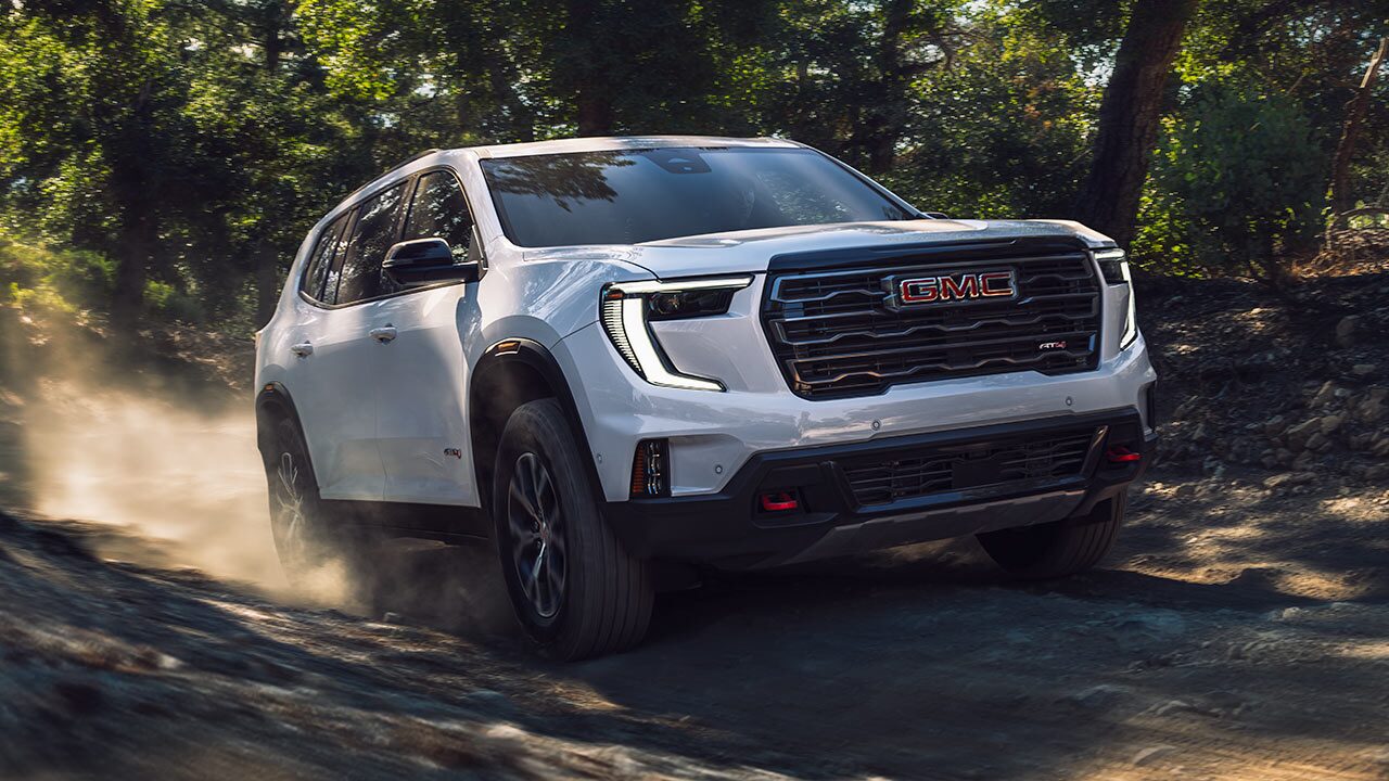 The GMC Yukon AT4 Full-Size Off-Road SUV Driving Down a Dirt Road Through a Green Forest