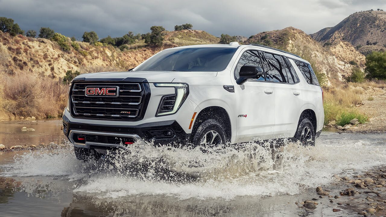 The GMC Yukon AT4 Full-Size Off-Road SUV Effortlessly Driving Through a Small Puddle of Standing Water