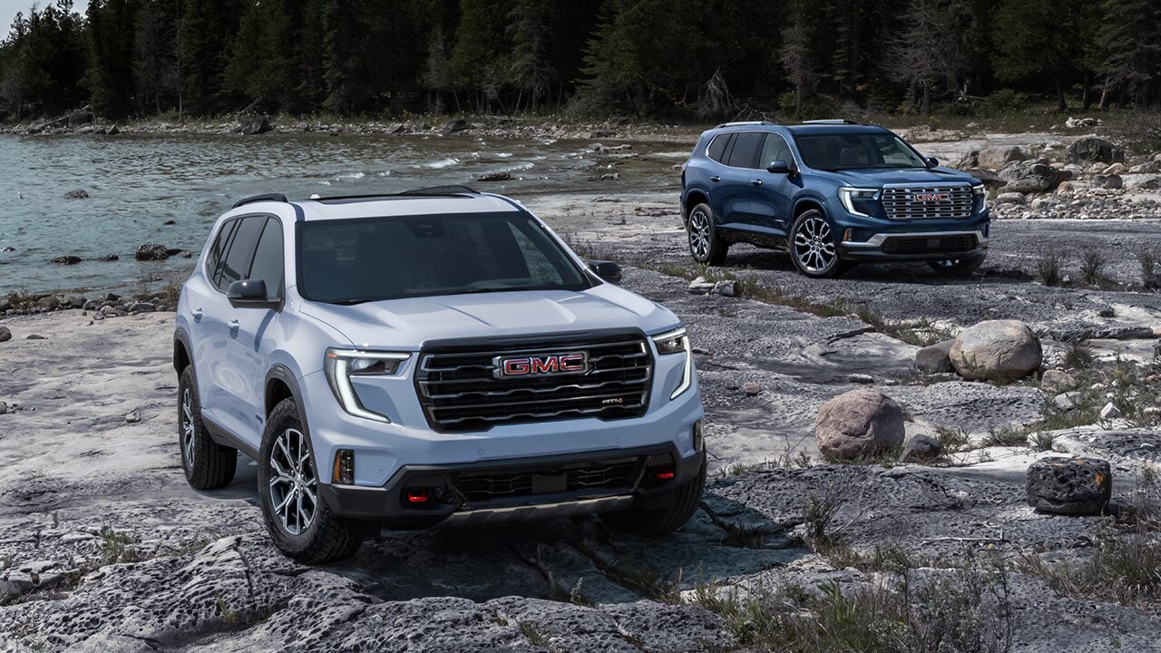 Two GMC Terrain AT4 Small Off-Road SUVs Parked on a Rocky Beach Next to a Large Body of Water