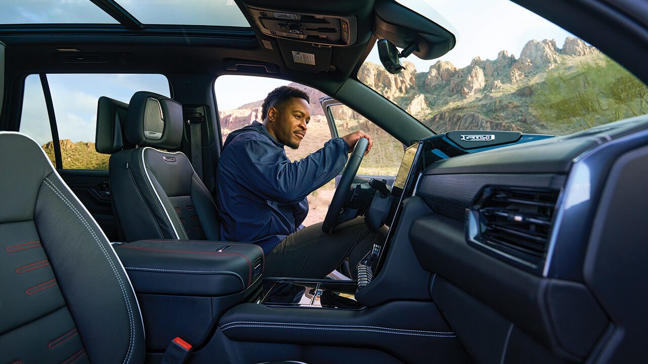 A Driver Stepping Out of the Open Door of His GMC Vehicle with a Scenic Mountain View in the Distance