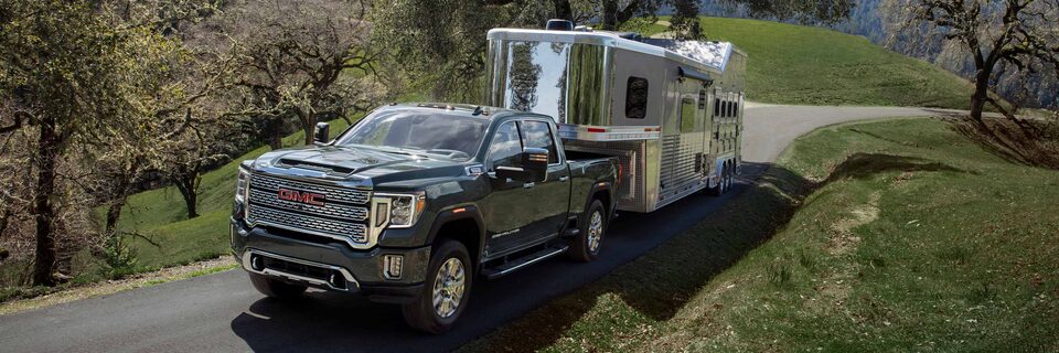GMC Sierra HD Heavy Duty Truck Pulling an Enclosed Trailer with Green Rolling Hills in the Background