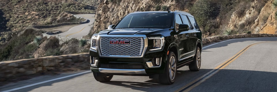 Front Three-Quarter View of a GMC Yukon Denali Driving up a Winding Mountain Road