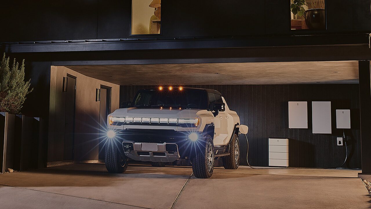 A White GMC Hummer EV Parked and Charging in a Modern Garage at Night with Home Energy Storage Units
