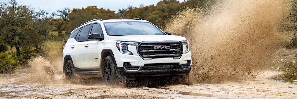 Three-Quarters View of a White GMC SUV Driving Through a Sandy Plane