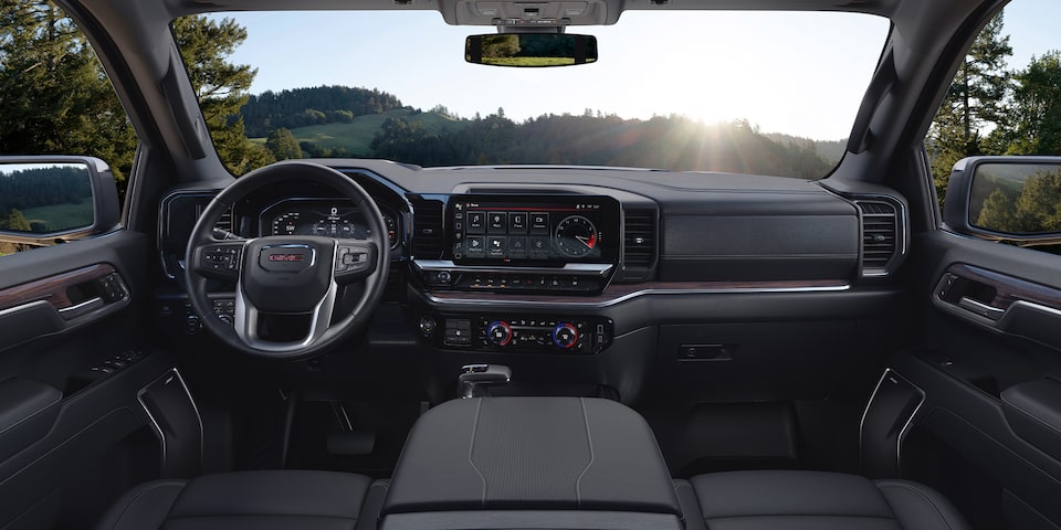The Interior Dashboard and Steering Wheel of the GMC Sierra Truck with a Green Valley View Through the Windshield