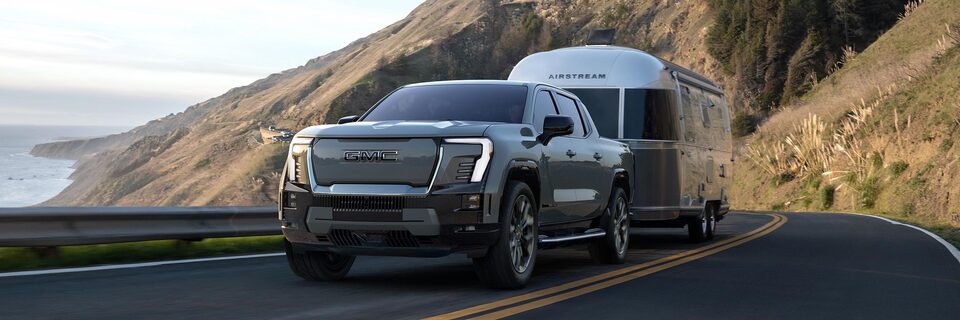 A GMC Sierra EV driving down the open road towing an Airstream.
