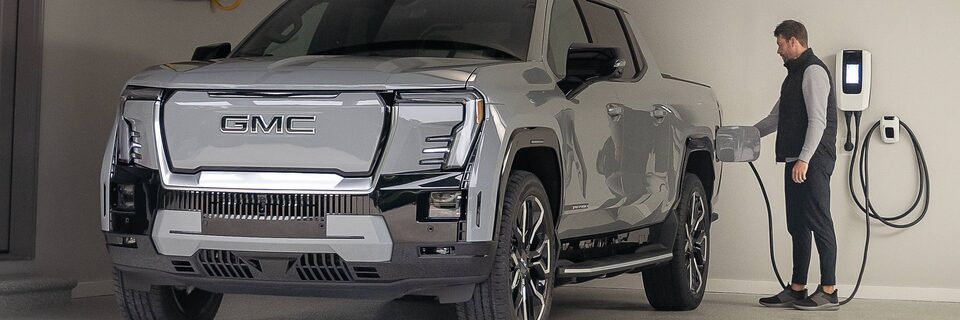 A man charging his Sierra EV pickup truck with his home charging station.