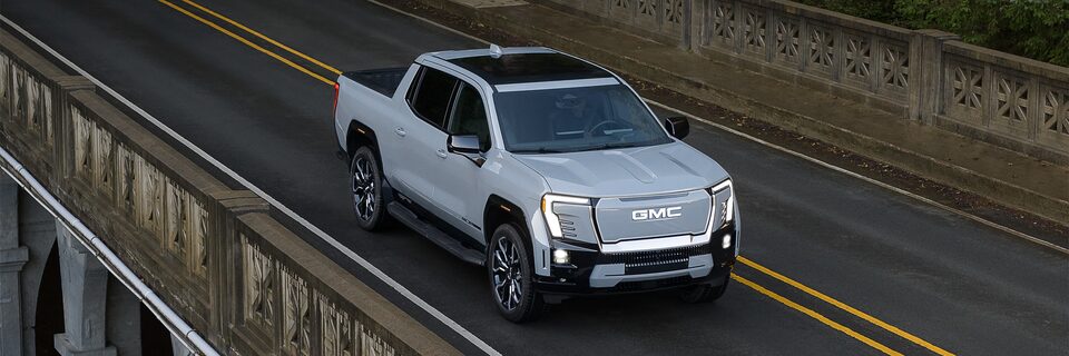 A birds-eye view of a GMC Sierra EV driving over a bridge.